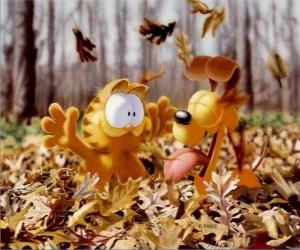 puzzel Garfield en Odie spelen met gevallen bladeren in de herfst