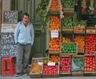 De verkoper van groenten en fruit in zijn winkel