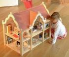 Meisje speelt met een pop en een poppenhuis met meubels