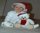Jongen met een Santa Claus hoed met zijn teddybeer