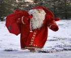 Santa Claus die de grote zak van giften van Kerstmis in het bos