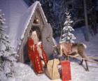 Santa aan de deur van zijn huis met een rendier en cadeaus