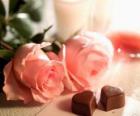 Twee roze rozen met twee chocolaatjes in hart-vormige