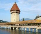 De houten en een overdekt bruggetje Kapellbrücke (de Kapel Bridge) en de toren Wasserturm in Luzern, Zwitserland