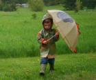 Jongen met zijn paraplu en regenjas onder de lenteregen